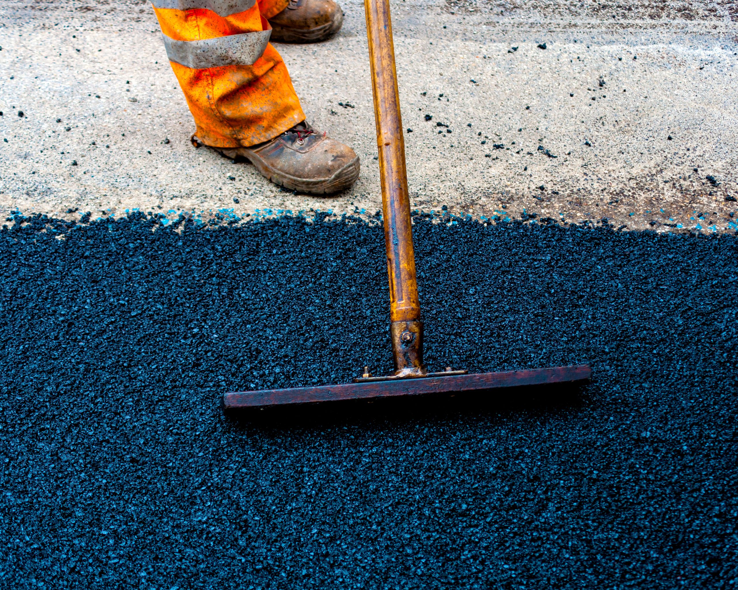 Worker on Asphalting paver machine during Road street repairing works